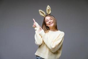 hermosa mujer joven en orejas de conejo muestra su dedo a lado en el fondo foto