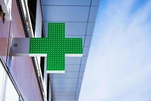 green cross on the facade of the building against the sky photo