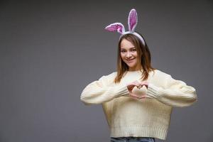 una chica con orejas de conejo en un fondo gris foto