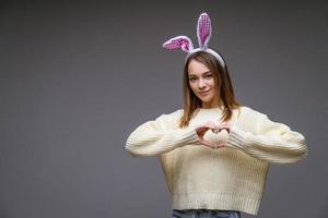 una chica con orejas de conejo en un fondo gris foto