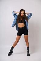 Cheerful young woman is dancing on a light background in a denim jacket photo