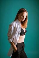 Young woman in white shirt and black lingerie posing in studio photo