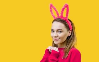 young woman in bunny ears on a yellow background photo