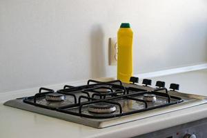 The cleaning of the kitchen. Very dirty gas stove. Cleaning the gas stove with a cleaning agent. photo