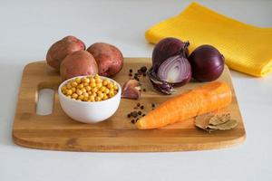 Ingredients for vegetable soup. Pea soup - potatoes, carrots, onions, garlic, peppers and peas on a wooden board. Rustic style. photo