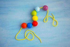 Developmental children's toy. Colored wooden balls on a rope. Colorful wooden baby beads for necklace. photo