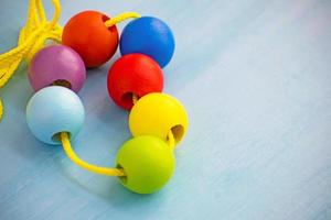 Developmental children's toy. Colored wooden balls on a rope. Colorful wooden baby beads for necklace. photo