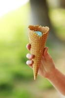 ice cream horn in a woman's hand. Delicious ice cream melts and flows to the horn in the woman's hand photo