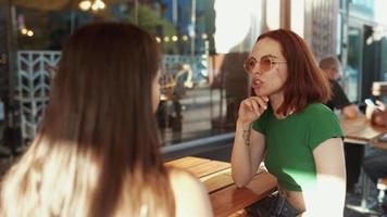 Zwei Frauen unterhalten sich und hängen im sonnigen Café ab