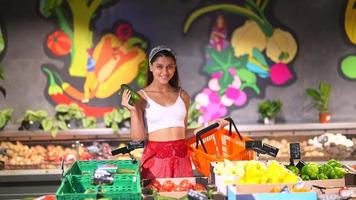 junge schöne Frau kauft auf dem Markt für frische Produkte ein video
