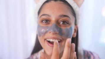 Young beautiful woman applies mask on nose and cheeks video