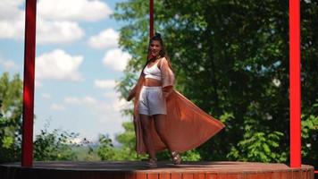 Woman in long flowy robe dances and smiles outside in sunshine video