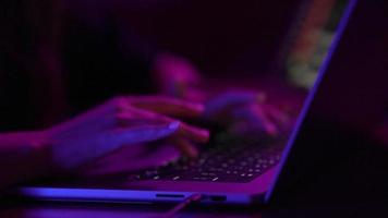 Young woman in a dark purple room uses a laptop video