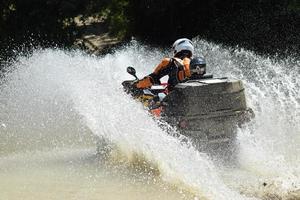 el hombre en el atv cruza un arroyo foto