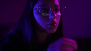 Young woman in a dark purple room uses a laptop