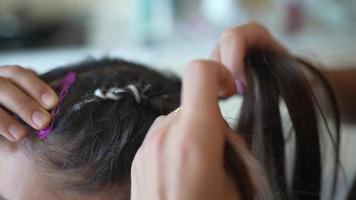 Girls braiding hair with a white strand of hair video