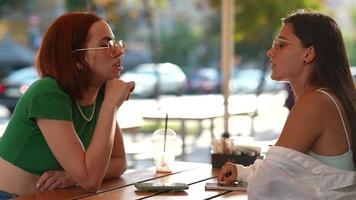 Zwei Frauen unterhalten sich und hängen im sonnigen Café ab