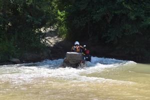 The man on the ATV crosses a stream photo