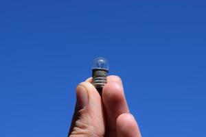 Bulb on 3 volts in a hand against the sky photo