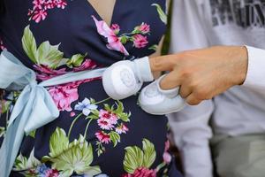 botines del futuro bebé en los dedos del padre, el padre camina sobre el estómago de la madre foto