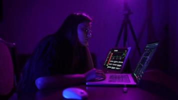 jong vrouw in een donker Purper kamer toepassingen een laptop video