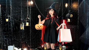 Beautiful woman dressed as witch for Halloween holding lantern pumkin and shopping bag in holloween theme photo