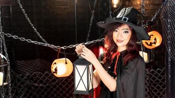 Happy halloween day. Portrait Asian woman in halloween costume witch black hat carrying lantern. photo