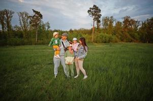 padres con tres hijos divirtiéndose juntos en el prado. foto