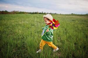 Babay girl with pinwheel at meadow. photo