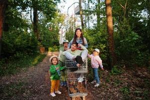 madre e hijos con carro divirtiéndose en el bosque. foto