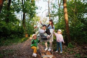 madre e hijos con carro divirtiéndose en el bosque. foto
