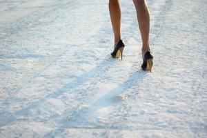 cropped photo of female legs in shoes on snow. selective focus