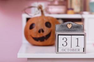 calendario de madera muestra la fecha 31 de octubre día de halloween y calabaza en la mesa de la escuela de madera en la habitación rosa de las niñas. concepto de decoraciones de halloween foto