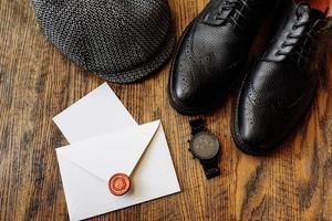 trajes de hombre para ropa de hombre con zapatos clásicos negros, reloj y sombrero gris vintage aislado sobre fondo de madera. vista superior. foto