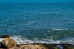 río de janeiro, rj, brasil, 2022 - gente pescando en una roca cerca de la pequeña playa, prainha foto