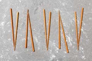 Many bamboo chopsticks on black cement stone background, top view with copy space. a lot of sushi sticks in the form of an ornament photo