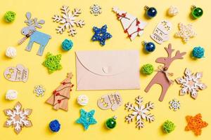 Top view of craft envelope on yellow background with New Year toys and decorations. Christmas time concept photo