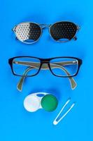 Medical concept. A set of accessories for sight. Top view. Pinhole glasses, lenses with container and glasses for sight photo