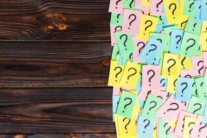 Too Many Questions on wooden background. Pile of colorful paper notes with question marks. top view copy space photo