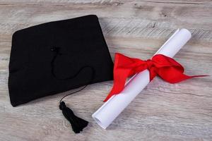 gorra de graduación, sombrero con papel de grado en concepto de graduación de mesa de madera foto