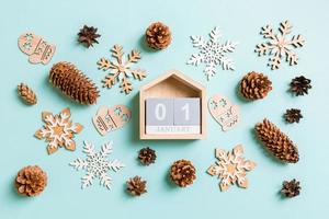 Top view of wooden calendar, holiday toys and decorations on blue Christmas background. The first of January. New Year time concept photo