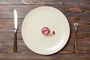 Round plate with measure tape inside with fork and knife on wooden background. Top view of obesity concept photo