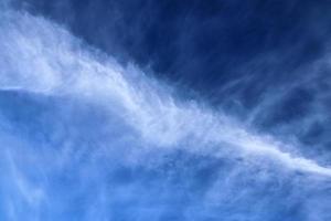 Estelas de condensación de aviones en el cielo azul entre algunas nubes foto