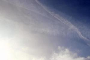 Estelas de condensación de aviones en el cielo azul entre algunas nubes foto