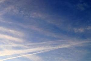 Estelas de condensación de aviones en el cielo azul entre algunas nubes foto