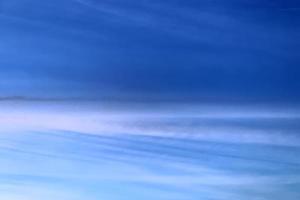 Aircraft condensation contrails in the blue sky inbetween some clouds photo