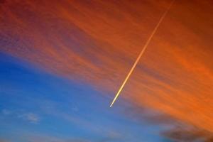 Estelas de condensación de aviones en el cielo azul entre algunas nubes foto