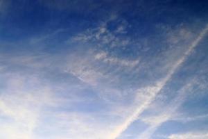 Estelas de condensación de aviones en el cielo azul entre algunas nubes foto