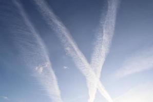 Estelas de condensación de aviones en el cielo azul entre algunas nubes foto