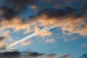 Estelas de condensación de aviones en el cielo azul entre algunas nubes foto